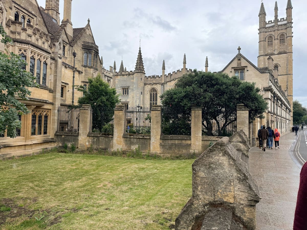 People walk past historic stone university buildings