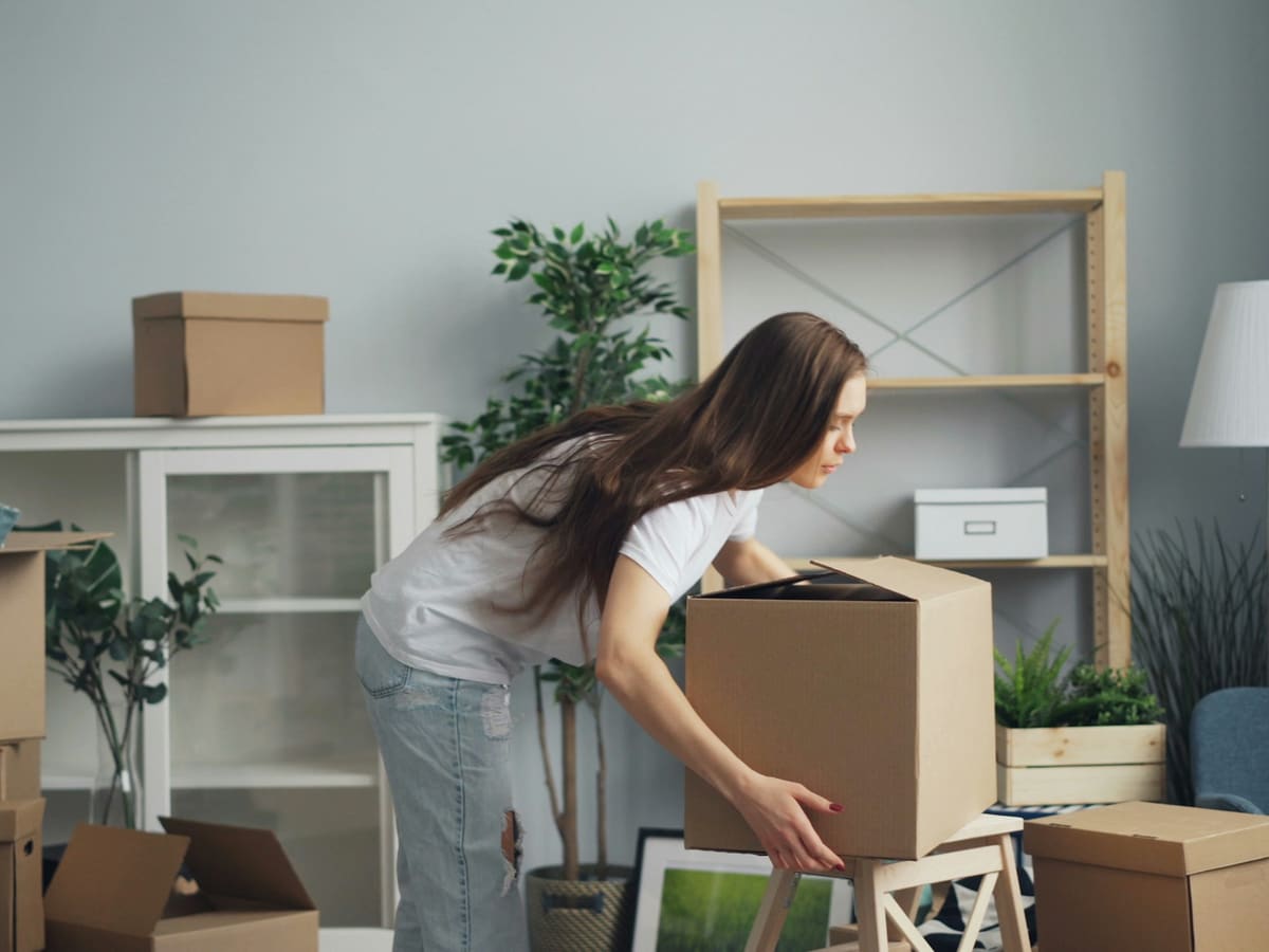 a woman moving boxes in a living room
